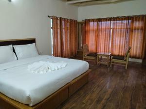 a bedroom with a large bed and two chairs at Two Flower Guest House in Leh