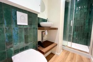 ナンシーにあるNancy Pépinière Appartement rénové et équipéの緑のタイル張りの壁、トイレ付きのバスルーム