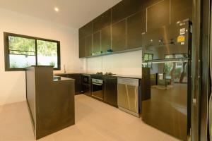 a kitchen with stainless steel appliances and brown cabinets at Samui Paradise Poolside Villa in Nathon Bay