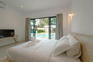 a white bedroom with a bed with two rabbits on it at Samui Paradise Poolside Villa in Nathon Bay +39 photos