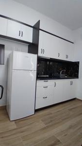 a kitchen with white cabinets and a white refrigerator at Rentrooms Geni in Ksamil