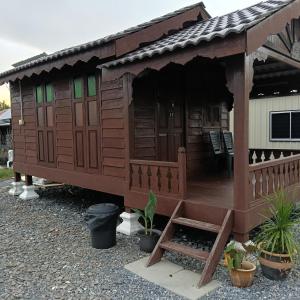 a small wooden house with a porch and chairs at Chinta Chinta Cottage Chalet Kayu in Arau +12 photos