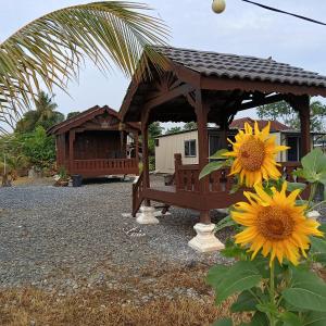 a wooden gazebo with a sunflower next to a house at Chinta Chinta Cottage Chalet Kayu in Arau