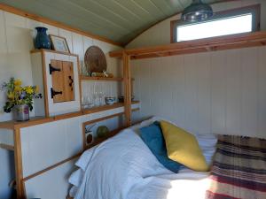 a bedroom with a bed with a yellow pillow and a window at Steam and Stars Luxury Glamping in Williton