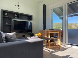 un salon avec un canapé, une table et une télévision dans l'établissement Lilikas Sea Front Apartments 4, à Lilikás