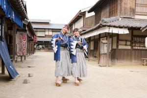 two women are riding skateboards down a street at Homm Stay Nagi Arashiyama Kyoto By Banyan Group in Kyoto