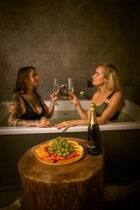 two women in a bath tub holding glasses of wine at Wellness Plus in Hrabŭvka
