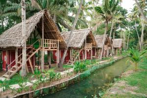 a row of bamboo huts next to a river at TempleTree Inn in Varkala