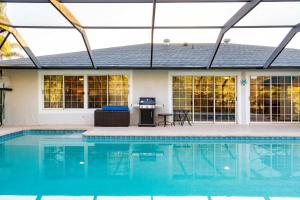a swimming pool with a glass roof over a house at Family-Ready 4BR with Heated Pool & BBQ in North Fort Myers +49 photos