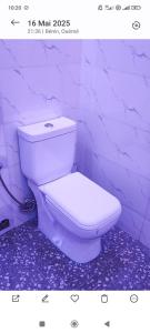 a white toilet in a bathroom with a purple wall at Résidence Yemissi in Cotonou