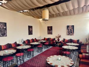 ein Raum mit Tischen, Sofas und roten Stühlen in der Unterkunft Riad Hotel Sherazade in Marrakesch