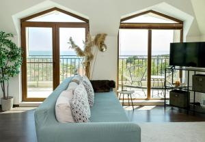 een woonkamer met een blauwe bank en een televisie bij Panoramic Sea-View I 2-Bedroom Flat with Terrace by Flat Manаger in Balchik