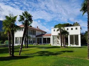 a white house with palm trees in the yard at Villa Delta - Parkhotel Delta in Ascona