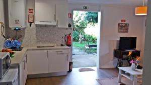 eine Küche mit weißen Schränken und einer Tür zu einem Hof in der Unterkunft Ninho do Cedro - Azorean tranquility in Livramento