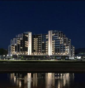 a large building at night next to a body of water at River Walk Sarajevo-Ilidza Best Apartman in Sarajevo