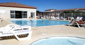 a swimming pool with white chairs and a woman sitting in a pool at Maison Solèna in Gallargues-Le-Montueux