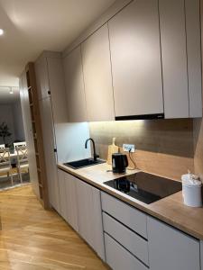 a kitchen with white cabinets and a sink at River Walk Sarajevo-Ilidza Best Apartman in Sarajevo