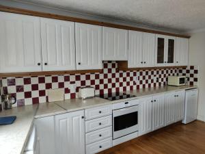 a kitchen with white cabinets and red and white tiles at Avondale Apartment Lahinch in Lahinch