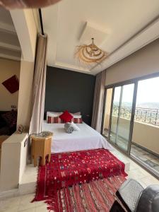 a bedroom with a large bed with a red rug at SurfAppart Morocco in Tamraght Ouzdar