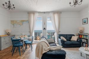 a living room with a table and chairs and the ocean at Balcony Apartment in Swanage