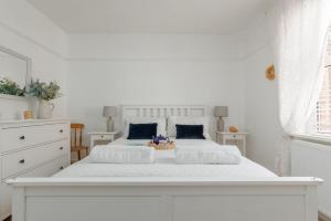 a white bedroom with a large white bed with blue pillows at Balcony Apartment in Swanage