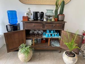 a wooden dresser with wine glasses and potted plants at Casa Katipunan in Manila