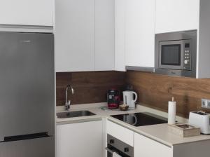 Una cocina blanca con fregadero y microondas. en El Mirador de El Retiro, en Madrid