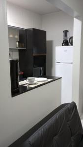 una cucina con bancone nero e frigorifero bianco di Apartamento Novo, Lindo e Confortável prox Centro a Gravataí