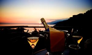 a bottle of wine and glasses on a table with the sunset at Sole Mare in Ventimiglia