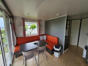 a living room with an orange couch and a table at Camping Aubeterre in Laprade