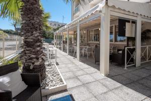 a resort patio with tables and chairs and a palm tree at Hotel Altamarea Cesenatico in Cesenatico