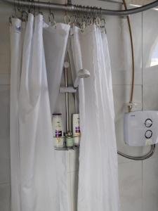 a bathroom with white shower curtains in a room at The Burren Art Gallery built in 1798 in Tubber
