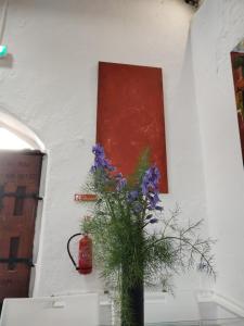 a vase with purple flowers on a wall with a painting at The Burren Art Gallery built in 1798 in Tubber