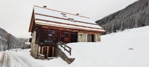 a small wooden cabin in the snow with a road at Chalet montagne 10 personnes in Ceillac