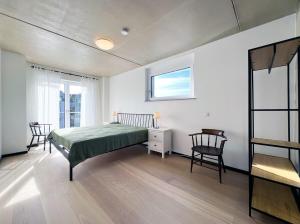 ein Schlafzimmer mit einem Bett und zwei Stühlen und einem Fenster in der Unterkunft bonquartier - Luxus in Natur - Penthouse nah Bonn in Wachtberg