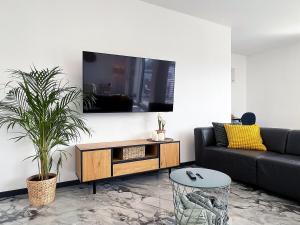 ein Wohnzimmer mit einem Sofa und einem Fernseher an der Wand in der Unterkunft bonquartier - Luxus in Natur - Penthouse nah Bonn in Wachtberg
