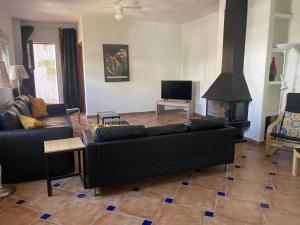 a living room with a black couch and a fireplace at Lovely 10-Bed Villa with Private Pool & Garden in Cacin