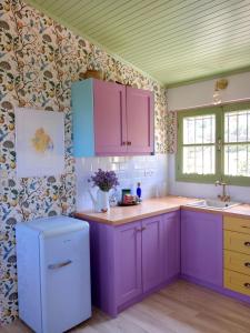 a kitchen with purple cabinets and flowers on the wall at Monemvasia's Art House in Ayía Kiriakí