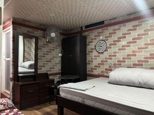 a bedroom with a brick wall and a mirror at Thapa Home Stay in Pokhara