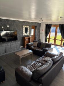 a living room with a leather couch and a flat screen tv at The Gatehouse in Upwell