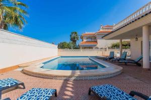 una piscina con sedie e una casa di Acogedor Chalet con piscina 2ª Línea del Mar Menor a Cartagena