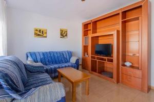 un soggiorno con un divano blu e una TV di Acogedor Chalet con piscina 2ª Línea del Mar Menor a Cartagena