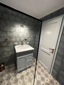 a bathroom with a sink and a white door at Plomari Grey house Casa Peppe in Plomarion +20 photos