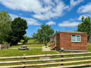 a wooden cabin in a field with a fence at Simene cabin in Bridport