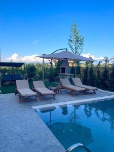 a pool with two lounge chairs and an umbrella at Pearl Pool Luxury Villa in Golem