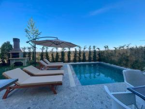 a swimming pool with two chairs and an umbrella at Pearl Pool Luxury Villa in Golem