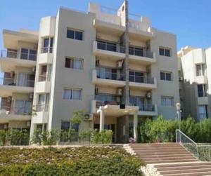 a large white building with stairs in front of it at شقة مميزة ارضى بحديقة بكمبوند ذا ادريس الشيخ زايد in Sheikh Zayed