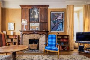 a living room with a fireplace and a blue chair at Le petit chateau in Vicq-sur-Breuilh