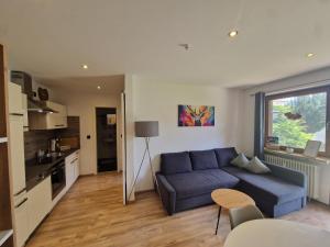 a living room with a blue couch and a kitchen at Sarah's Ferienwohnung in Füssen