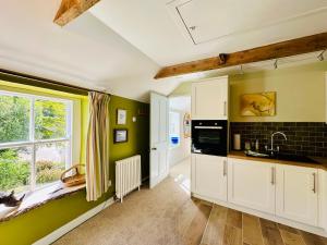 cocina con paredes verdes, armarios blancos y ventana en Exceptional retreat near Cornwall Coast, en Tywardreath